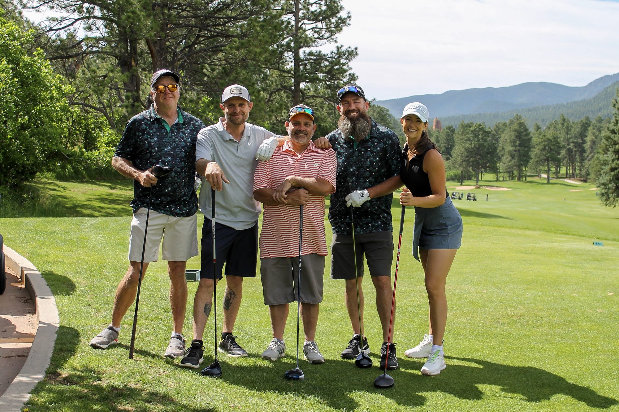 A foursome posing on the tee box with the mountains behind them